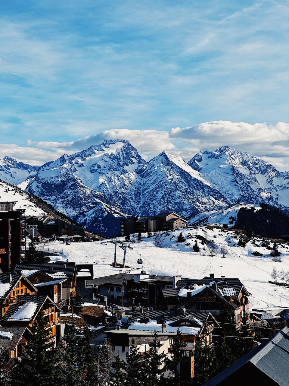 A view of a the town of Alpe d'Huez with the Alps in the background under a blue sky